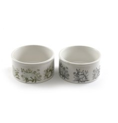 An assortment of 2 ceramic pet bowls each with a stylish forest toile design in earthy green and inky blue hues.