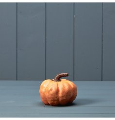 A ceramic pumpkin ornament with an orange glaze. A textured seasonal ornament. 