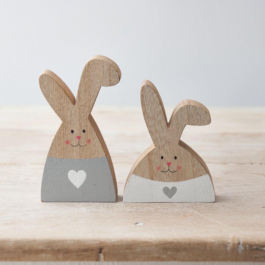 An assortment of 2 charming wooden rabbit decorations with grey and white painted hearts and cute smiling faces.