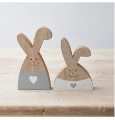 An assortment of 2 charming wooden rabbit decorations with grey and white painted hearts and cute smiling faces.