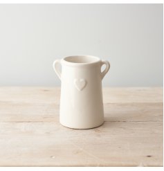 A white ceramic planter with eared design and embossed heart detail. 