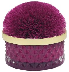 A luxury scented candle with jewel coloured cut glass pot and pom pom lid.