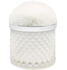 A luxury scented candle set within a glass pot with pom pom lid.
