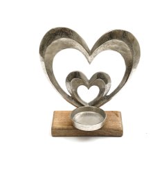 A beautiful heart shaped metal tea light holder on a wooden base.
