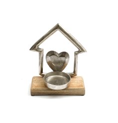 A house shaped tea light holder with heart detail on a wooden base.