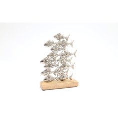 A decorative metal item depicting a shoal of fish on a wooden base.