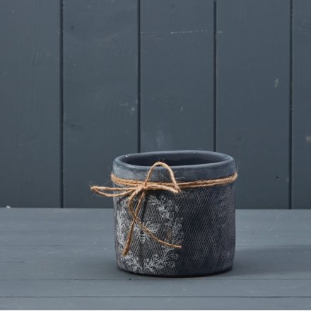 A rustic black planter with a rustic surface texture and charming bee and wreath design. 