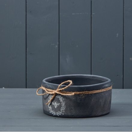 A rustic black bowl with a textured surface finish and attractive bee and wreath design. 