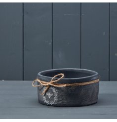 A rustic black bowl with a textured surface finish and attractive bee and wreath design. 