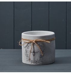 A charming plant pot with a textured surface and attractive bee and wreath design. Complete with a jute bow. 