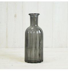 A stylish glass bottle with a ribbed surface texture and smokey grey colour. 