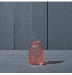 A beautiful rose pink glass bottle with a textured and patterned glass design.