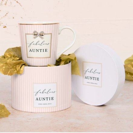 A pretty pastel pink mug with stripe design, bow charm, gold accents and "fabulous auntie" text.
