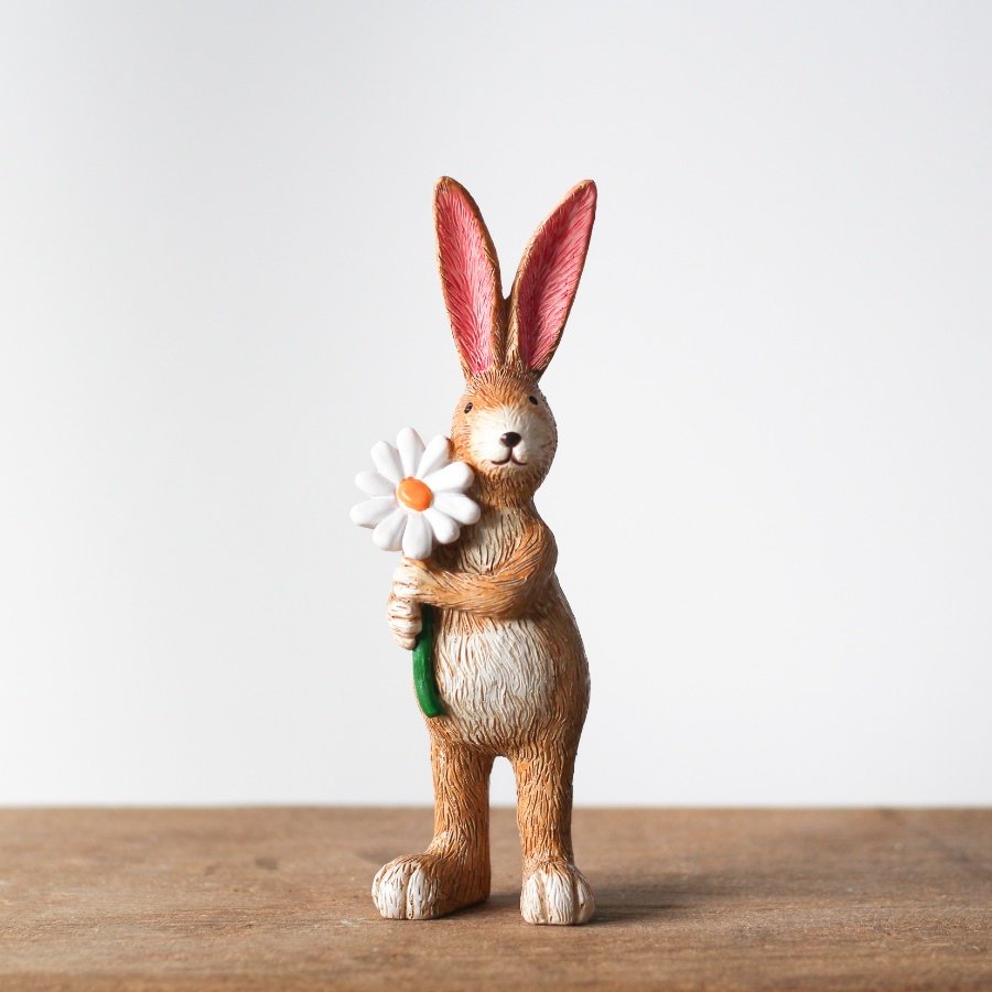 A charming rabbit figurine holding a pretty daisy.