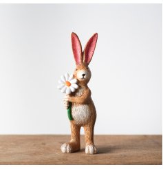 A cute decoration featuring a standing rabbit figure holding a daisy flower. 