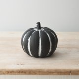 A stunning cement pumpkin, painted in black with white ridges. 