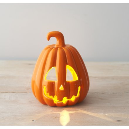 A stylish ceramic pumpkin shaped lantern with a spooky carved face and rich orange glaze. 