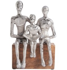 A beautiful item depicting parents sitting with a child, with a silver aluminium finish on a wooden base. 