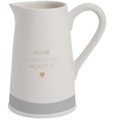 A white ceramic jug with delicate "home is where the heart is" text and heart detail. 