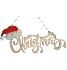 A wooden sign with "Christmas" text and decorated with snowflake details and Santa hat with fluffy trim. 