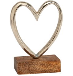 A stunning silver metal heart with cut out design presented on a contrasting wooden base. 
