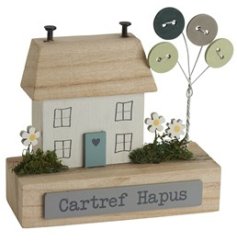 A decorative wooden house block with "happy home" written in Welsh, 3d detailing and button trees. 