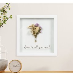 A box framed decorative sign displaying a mini dried bouquet with purple accents and "love is all you need" message. 