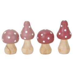An assortment of 4 wooden mushroom decorations each with a pinky/red design and white spots. 