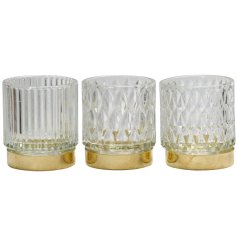 An assortment of 3 cut glass tea light holders, each with patterned glass and metallic gold base. 