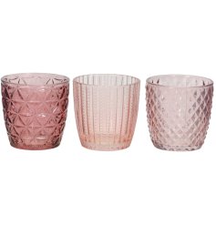 3 Assorted cut glass tea light holders each in a pretty pink colour each with a patterned finish. 