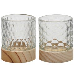 An assortment of 2 glass tea light holders, each with a patterned glass design and contrasting wooden base. 