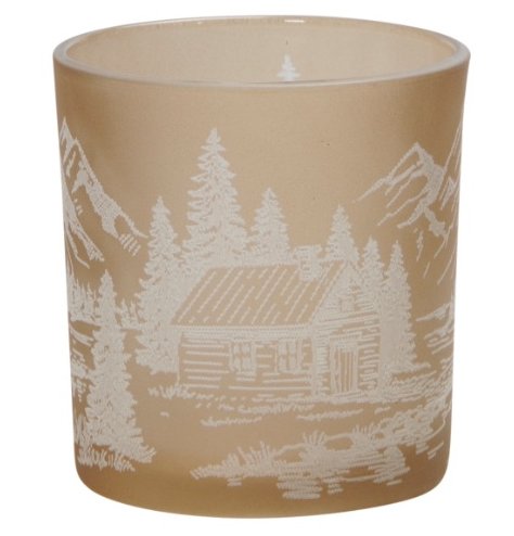 A fawn coloured glass tea light holder with a white snowy mountain range and log cabin design. 