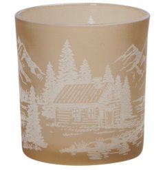 A glass tea light holder in a stylish fawn colour with a white mountain scene and log cabin pattern design. 