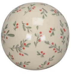 A decorative ceramic ball with a delicate red berry and green foliage pattern design. 
