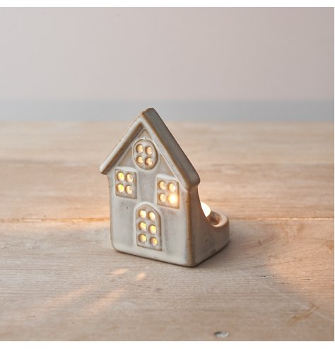 A rustic ceramic house t-light holder with cut out windows and a natural glaze.