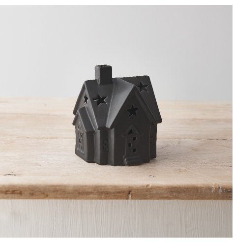 A stylish ceramic house with warm glow led lights. Beautifully detailed with cottage style windows and stars on the roof