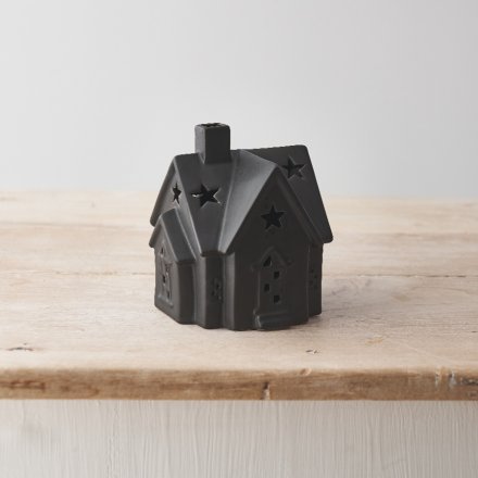 A stylish ceramic house with warm glow led lights. Beautifully detailed with cottage style windows and stars on the roof