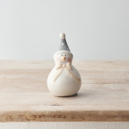 A cute snowman ornament with unique details including a draping polka dot bow and hat. 