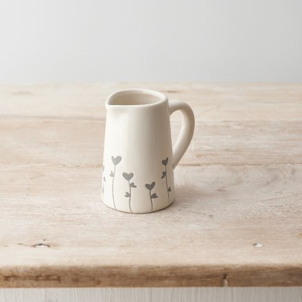 A pretty ceramic jug with a dainty heart flower design that wraps around the base. 