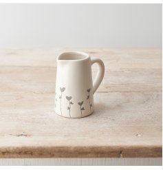 A pretty ceramic jug with a dainty heart flower design that wraps around the base. 