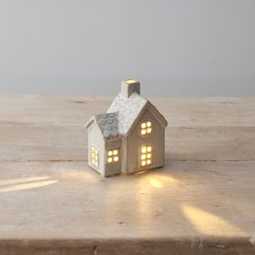 A cottage style ceramic house featuring a light up design with cut out detailing and patterned roof. 