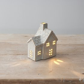 A ceramic cottage house with cut out detailing, scalloped pattern roof and light up feature. 