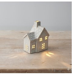 A ceramic cottage styled house featuring cut out detailing and light up feature with scalloped pattern roof. 