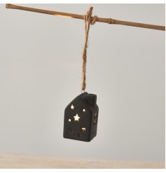 A unique ceramic house in black with cut out stars and a warm glow LED light. 