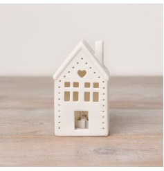 A white ceramic house shaped decoration featuring a light up design with cut out details including a sweet heart. 