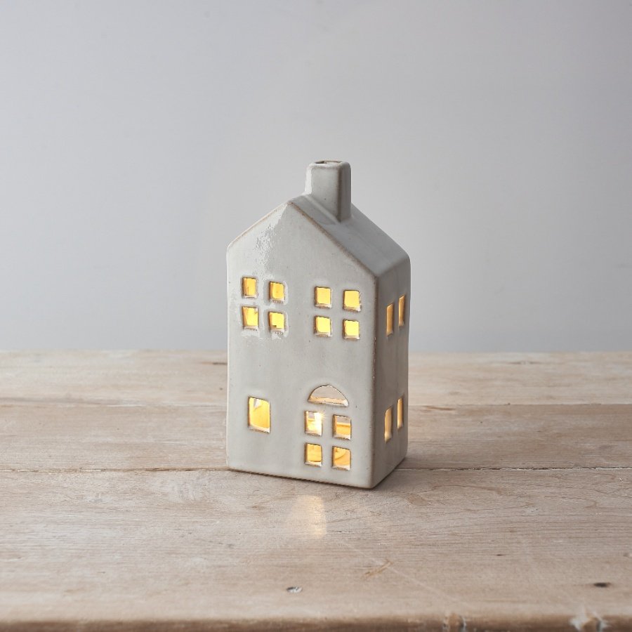 A natural ceramic house with led tea light, cut out details and rustic styling. 