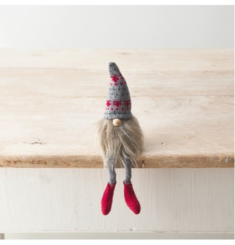 A shelf sitting fabric gonk decoration with dangly knitted legs, patterned hat, bead nose and fluffy beard. 