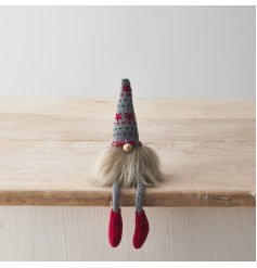 A cute shelf sitting gonk decoration with knitted legs and patterned hat with fluffy beard and bead nose. 