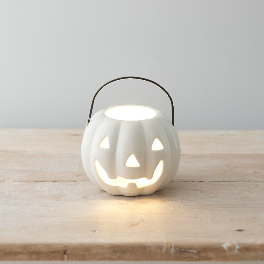 A stylish pumpkin shaped lantern with a carved traditional face and black carry handle. 