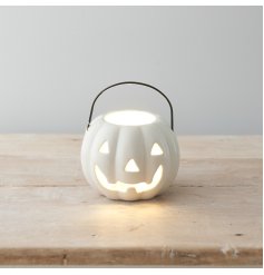 A fantastic white ceramic pumpkin shaped lantern with black handle and carved face.